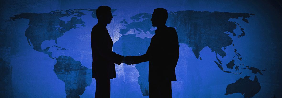 Два человека, рукопожатие с карты мира за ними