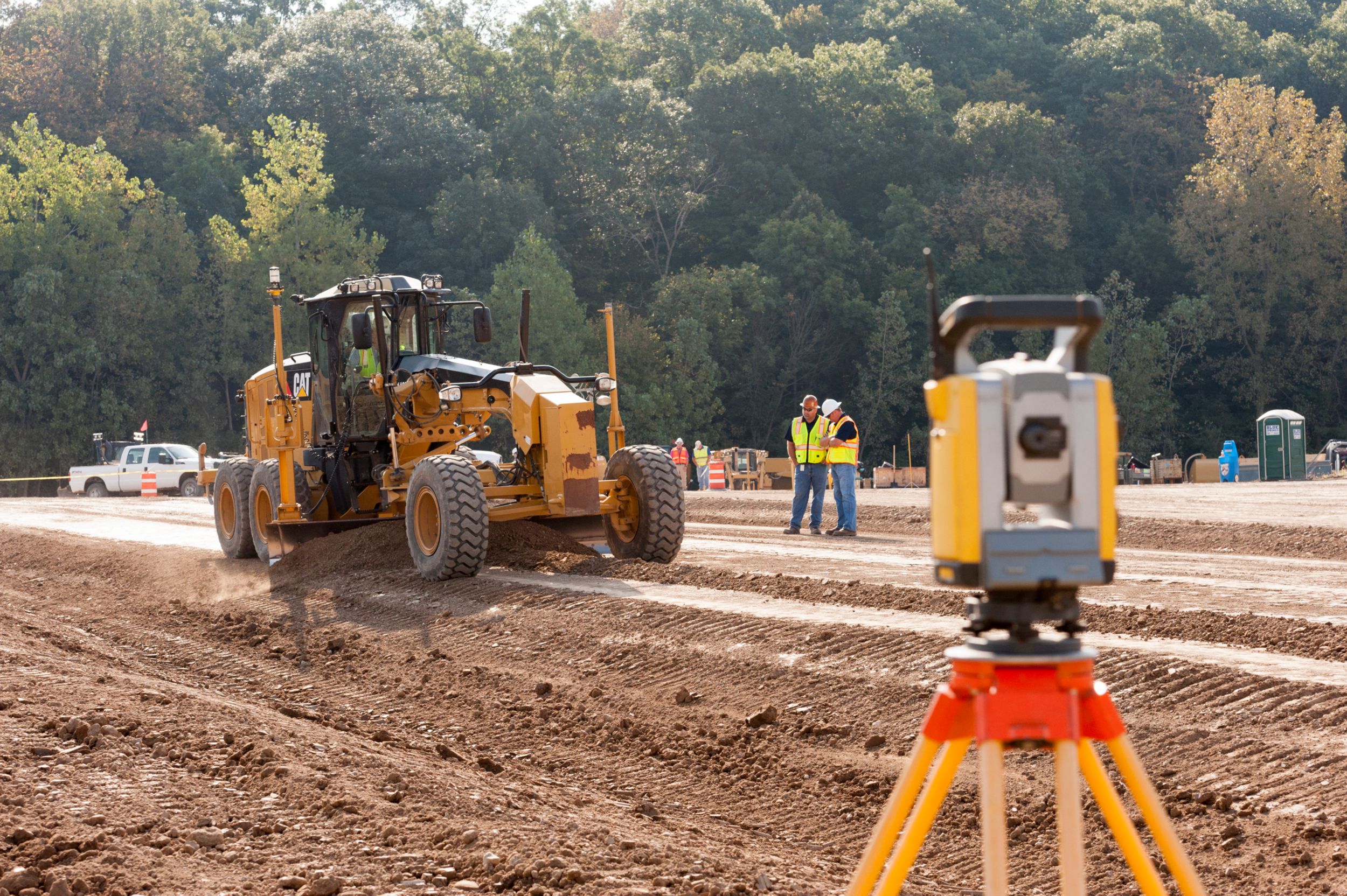 A motor grader uses Universal Total Station (UTS) to finish grade dirt subgrade in preparation for aggregate base course.