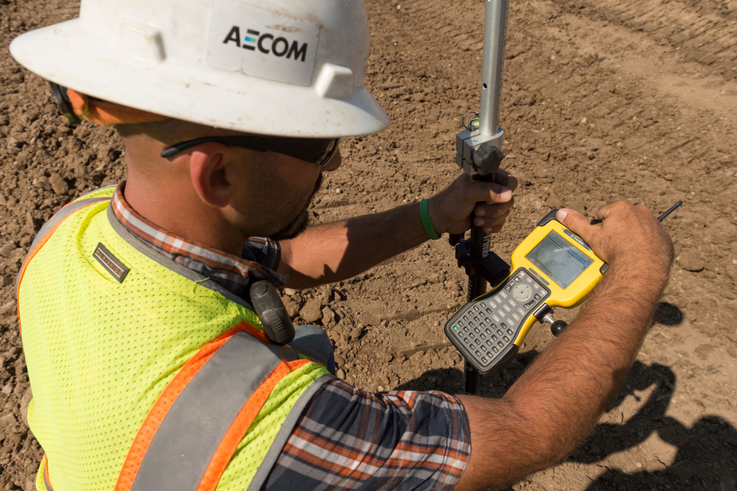 A laborer using a controller checks grade to determine cut or fill required.