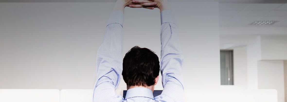 A man sitting at his desk stretching 