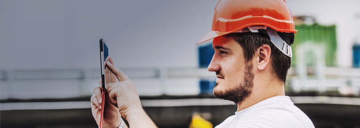 An operator in a hard hat takes a photo on his phone for Instagram