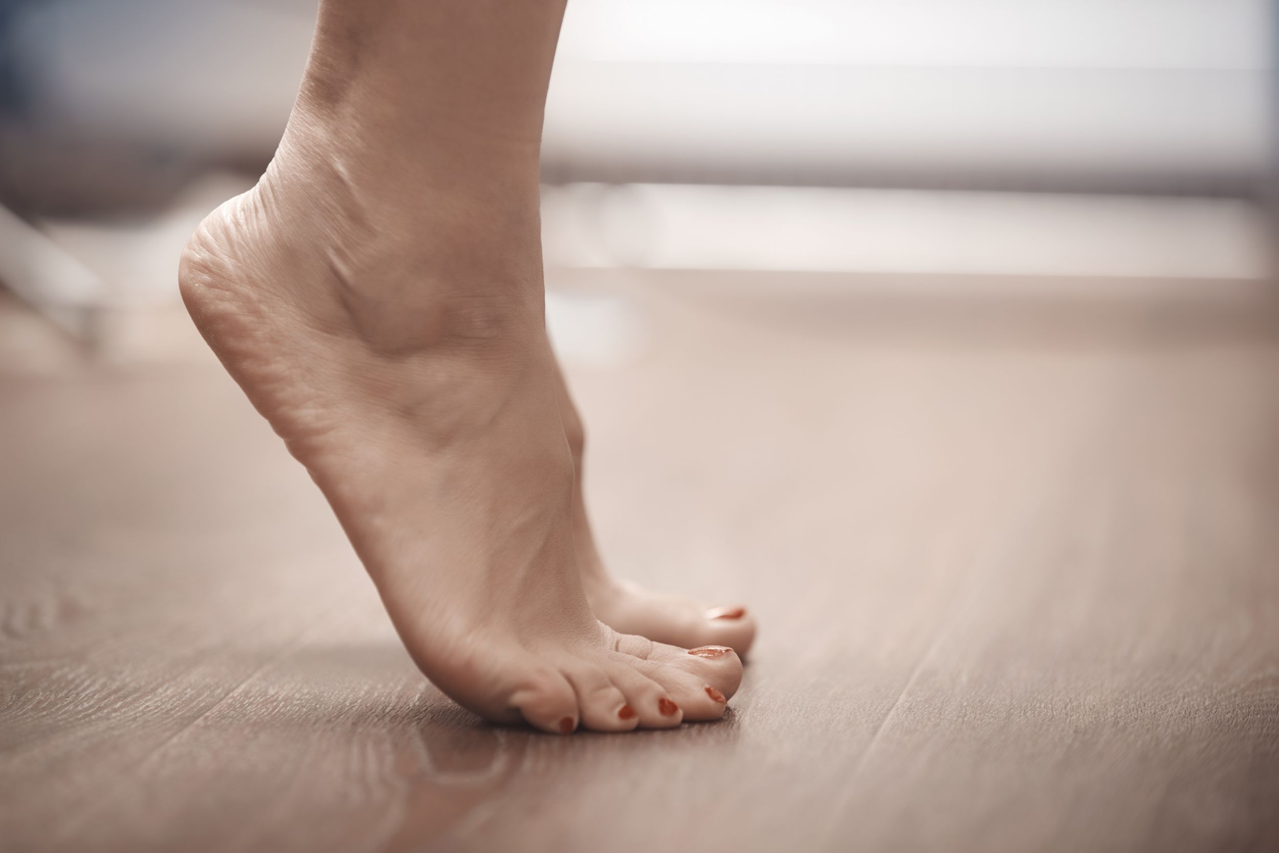 Photo of bare feet standing on tip-toes doing a calf stretch