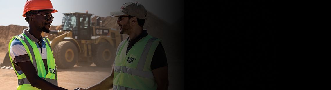 Technicians shaking hands in front of a wheel loader