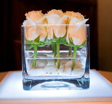 White roses in square glass vase with stones