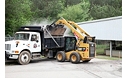Cat® Utility Broom Dumping Debris into waiting Dump Truck