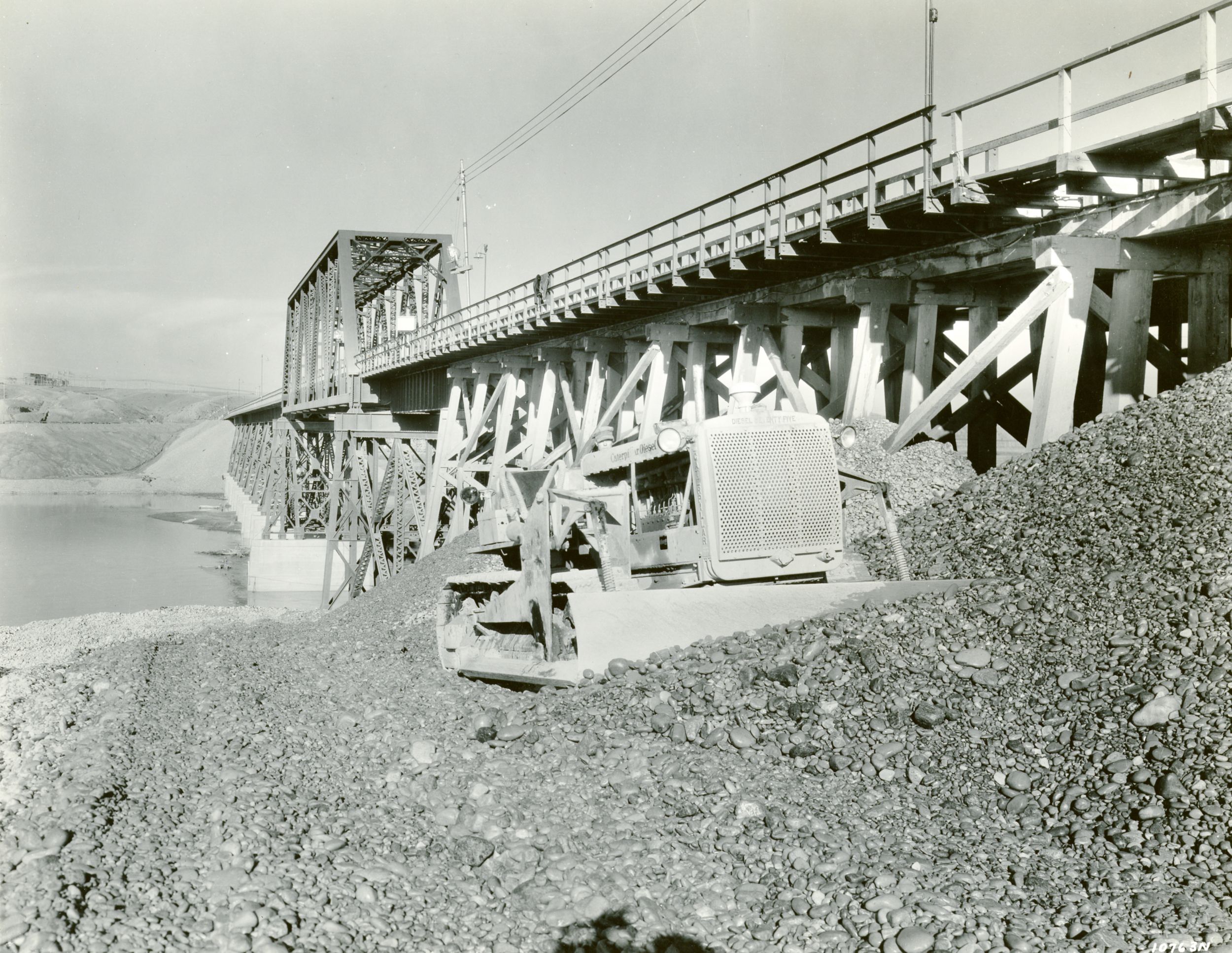 Caterpillar Diesel Seventy-Five track-type tractor equipped with a dozer leveling gravel at the Fort Peck Dam project in 1935.