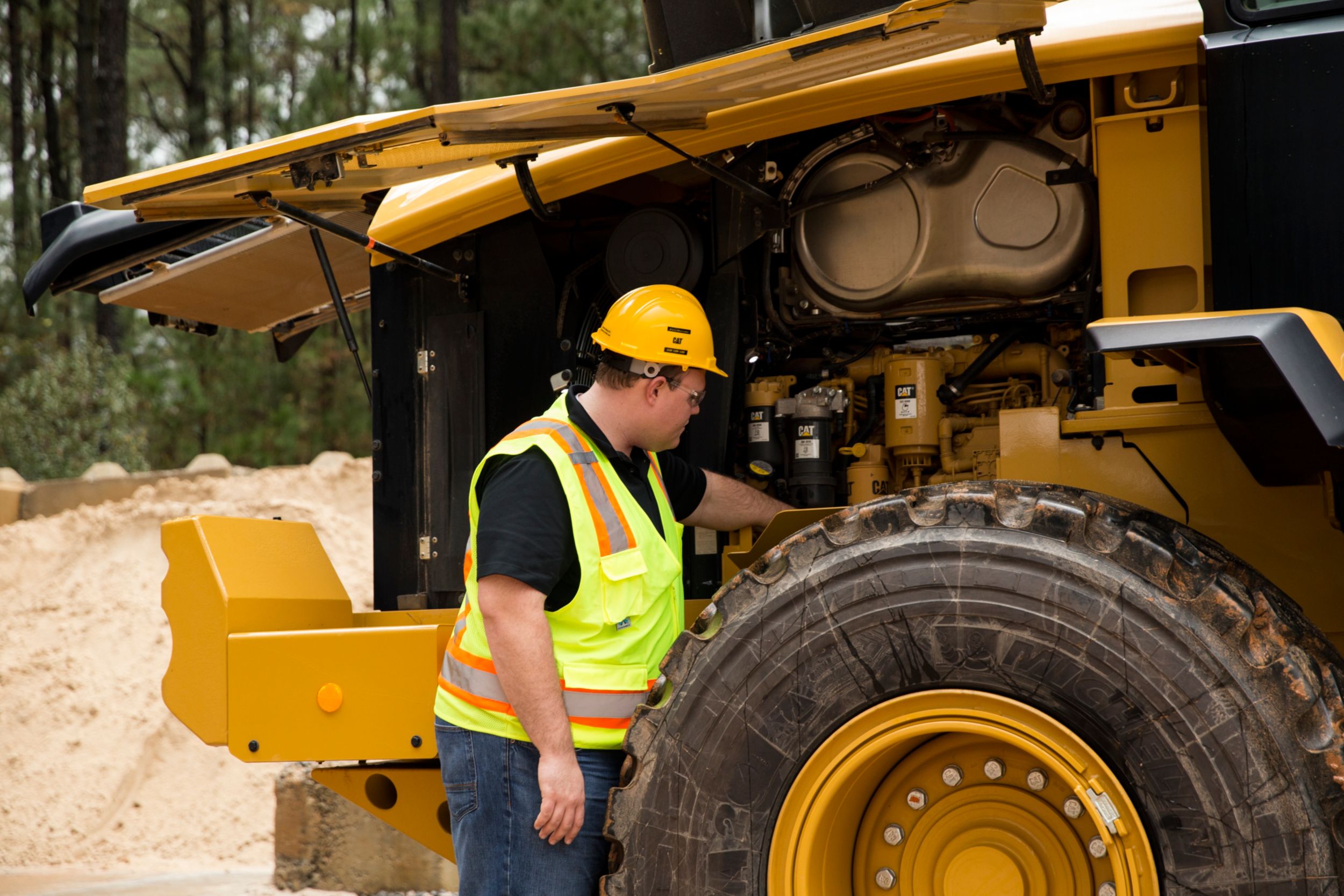 person performing maintenance on a small wheel loader