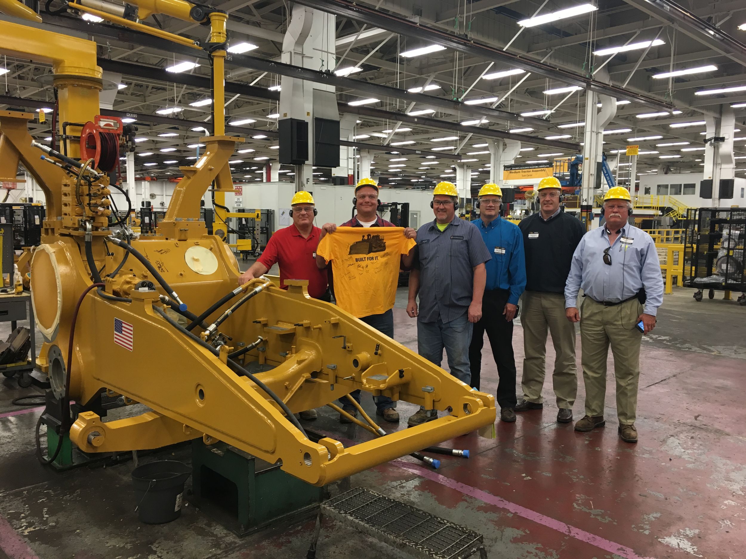 PDC employees and representatives from Altofer pose by the early stages of the tractor.
