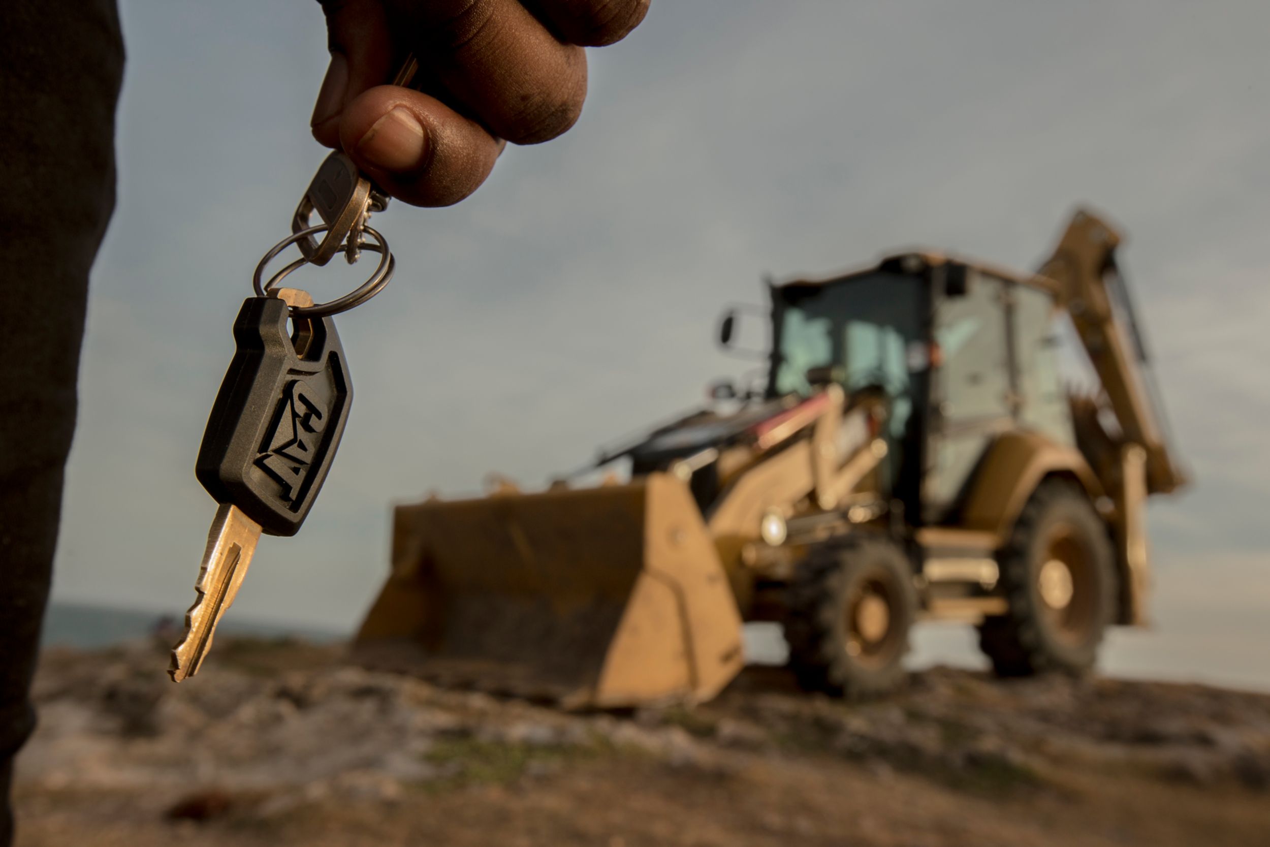 Backhoe loader and person holding key