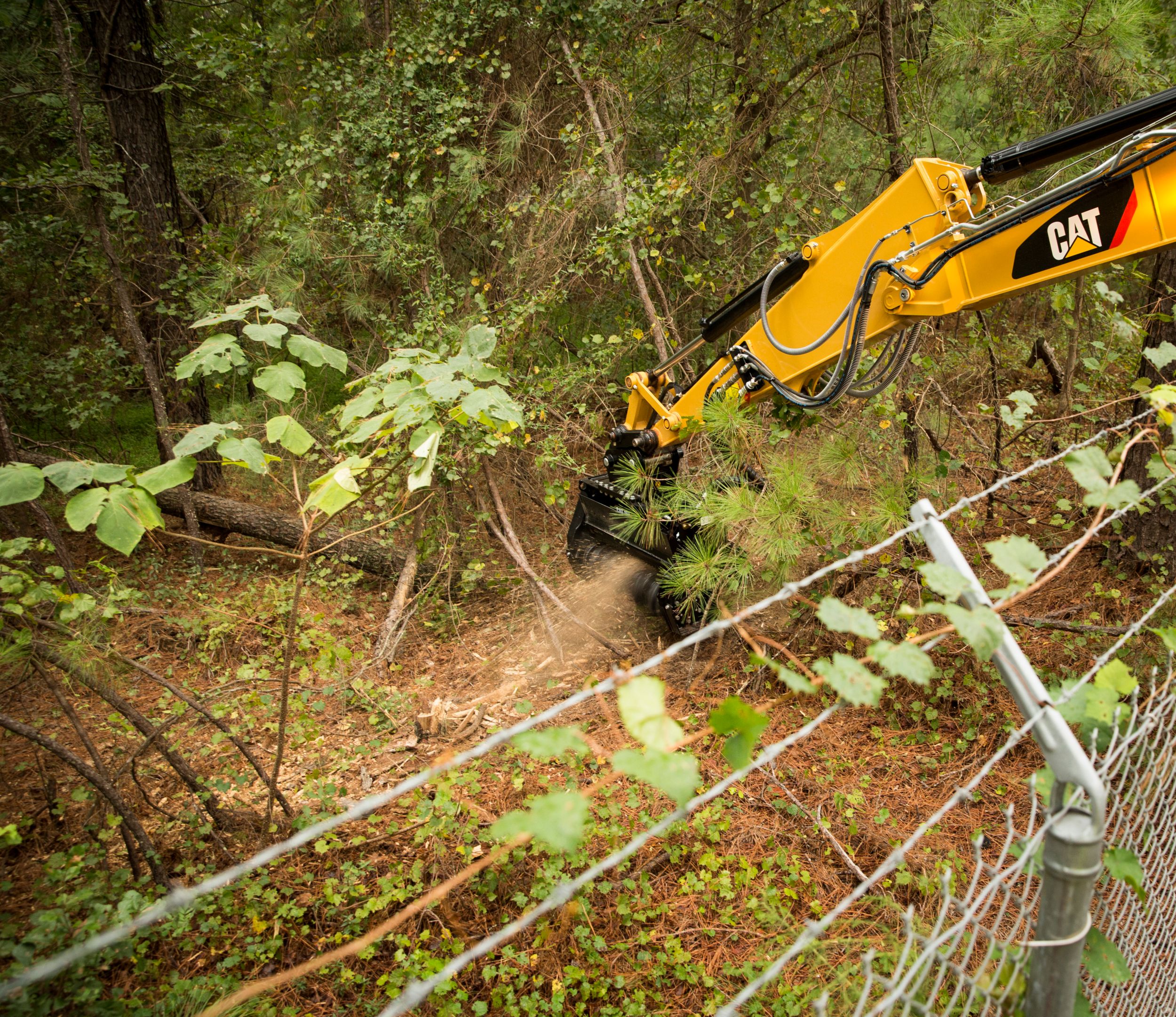 Cat® HM210 Mulcher Clearing Brush on Over a Fence>