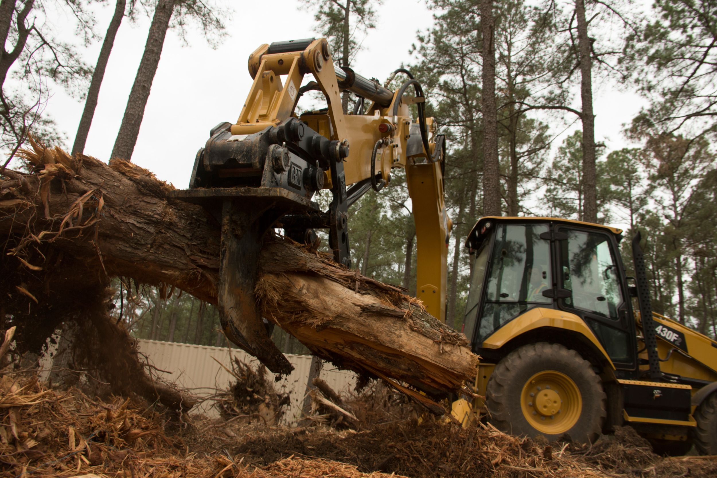 اللودر ذو محراث خلفي Cat® 420F2 مع الأداة الإبهامية والكسارة أثناء العمل