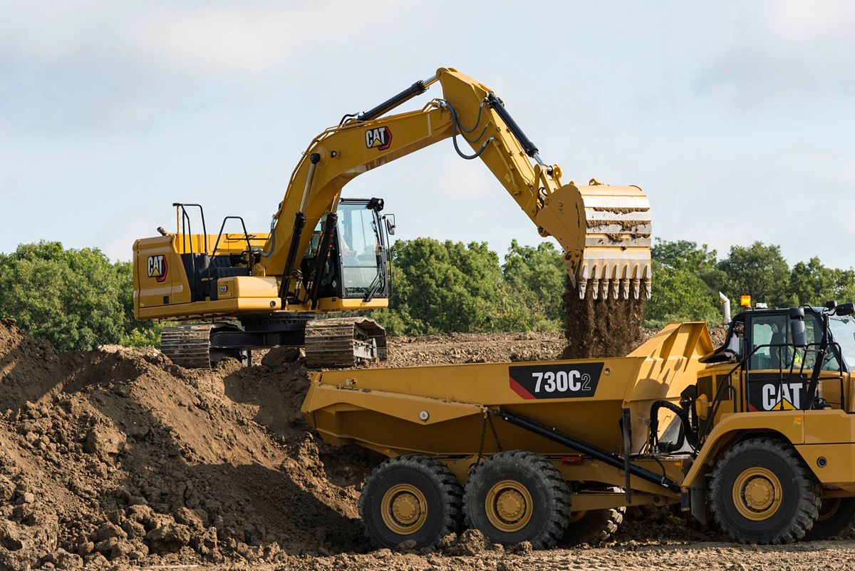 323 Hydraulic Excavator dumping dirt into an articulated truck