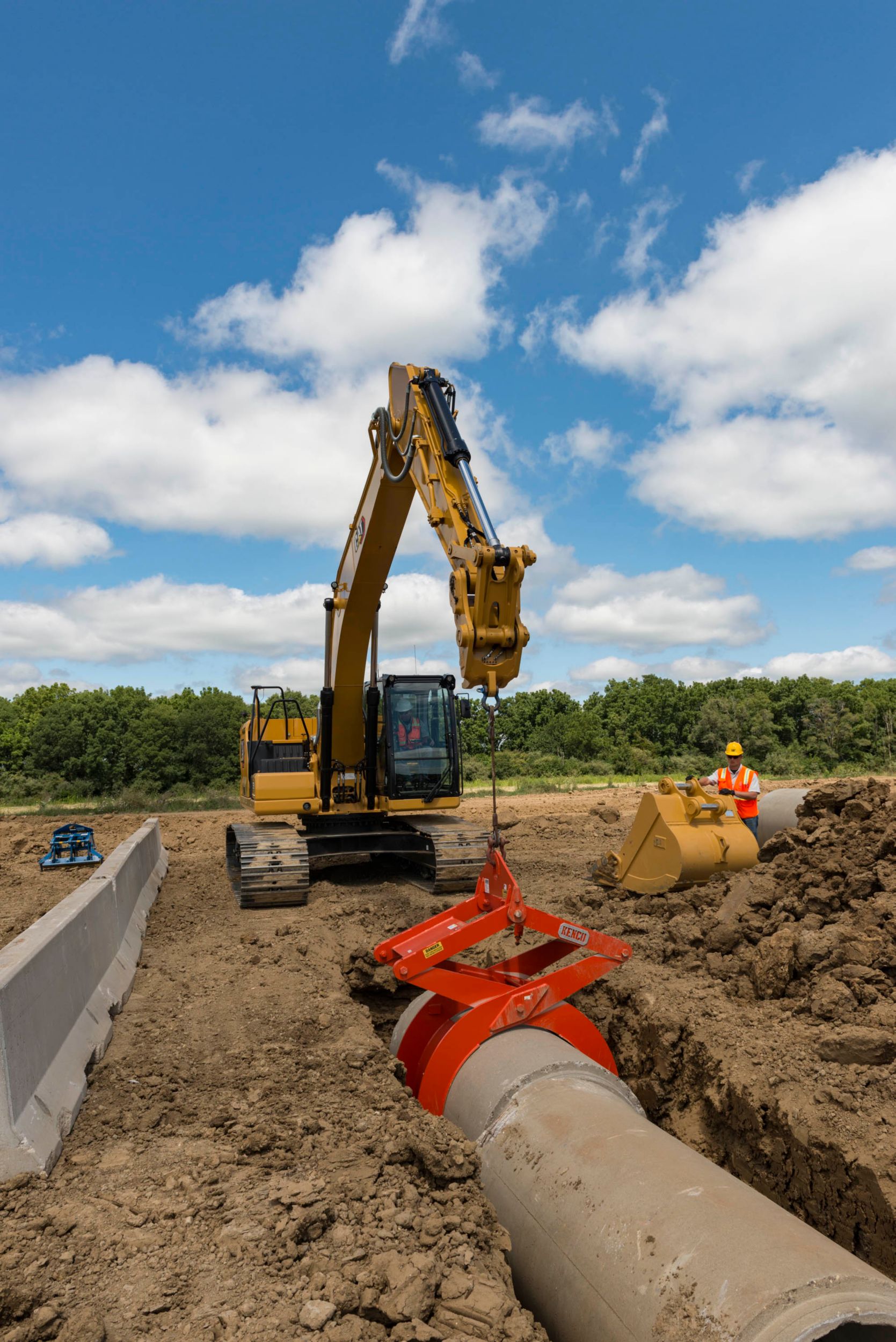 Pelle hydraulique 323 plaçant un tuyau de vidange en béton