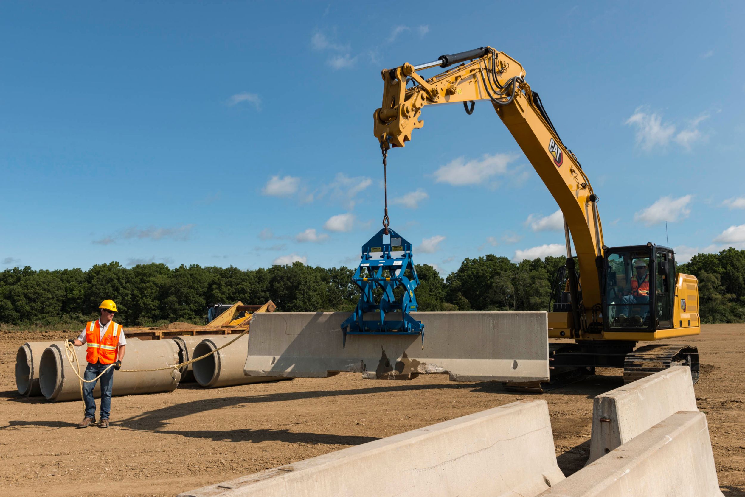 Średniej wielkości koparka hydrauliczna 320 podnosząca betonową barierę