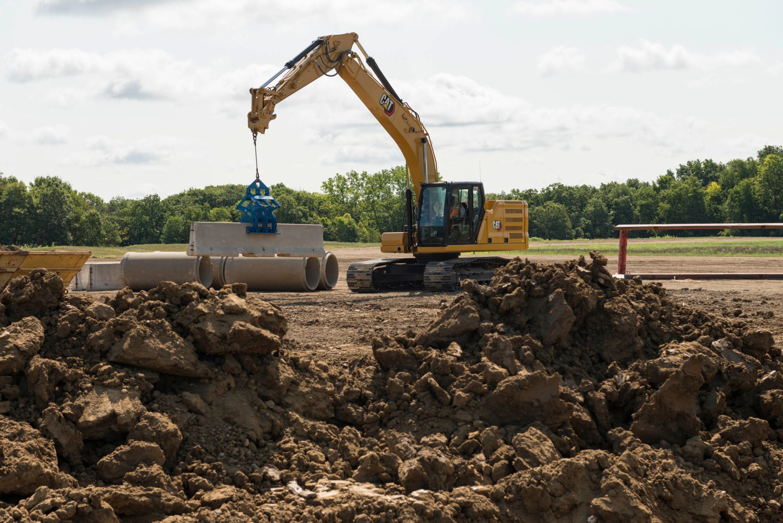 Średniej wielkości koparka hydrauliczna 320 stawiająca betonową barierę