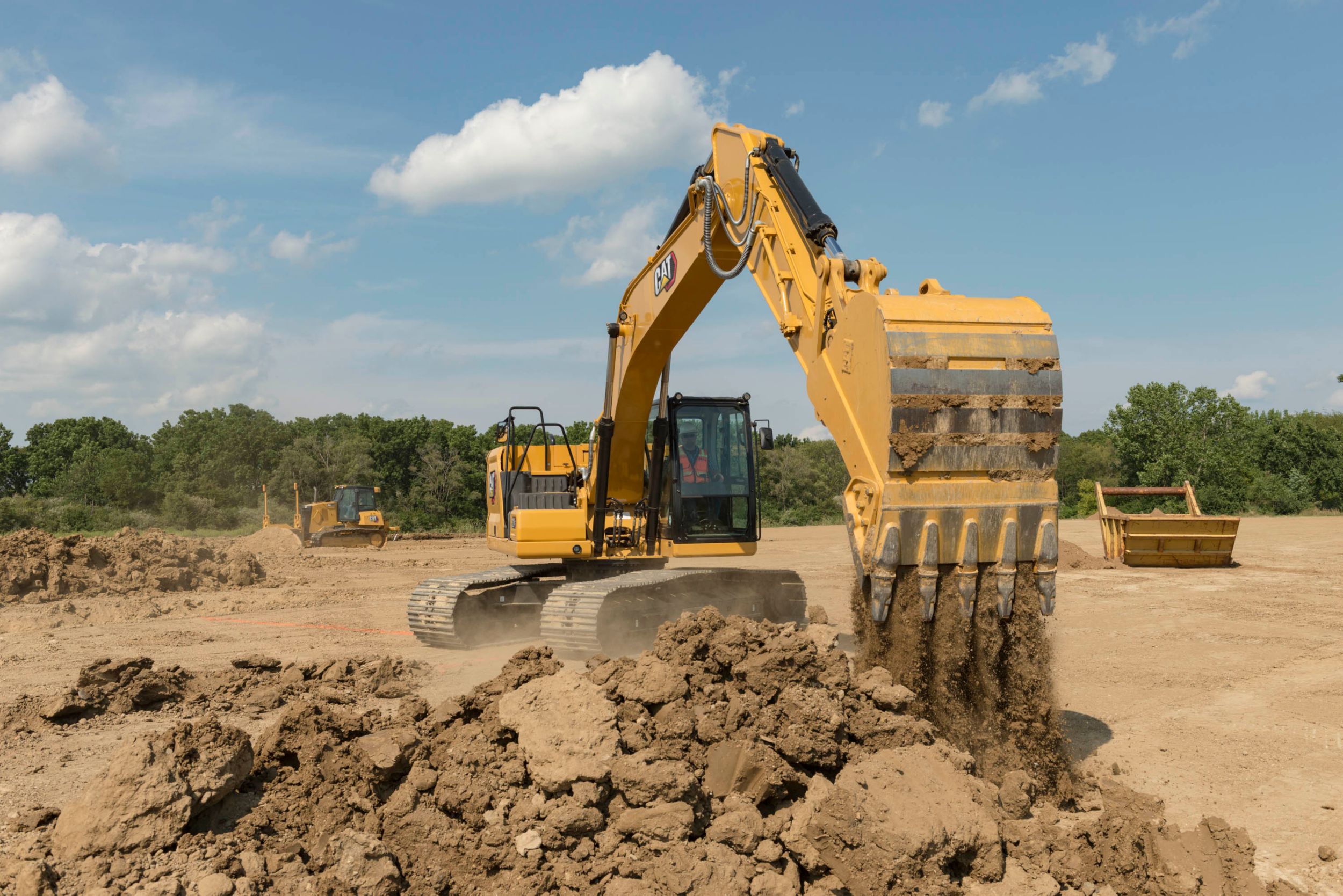 Graafmachine 320 GC die een laadbak met aarde stort