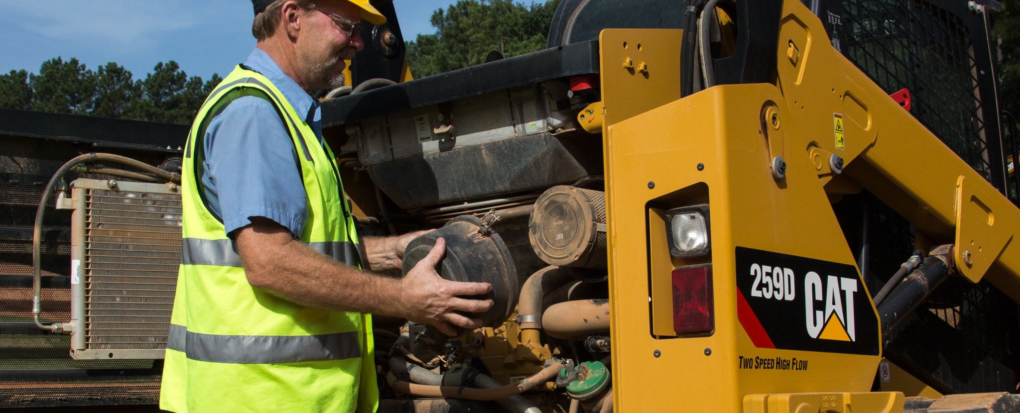 person performing maintenance on a compact track loader