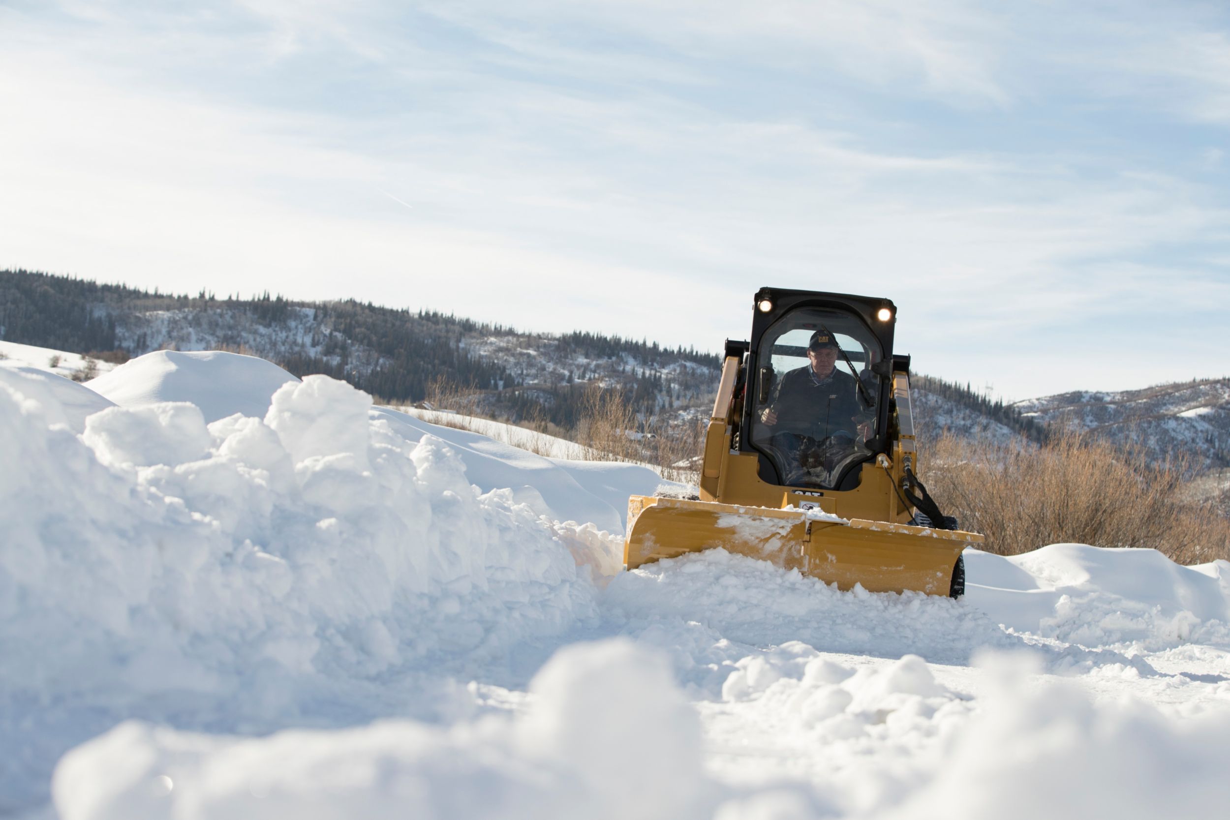 Chasse-neige en V multifonction Cat déplaçant la neige en configuration lame orientable