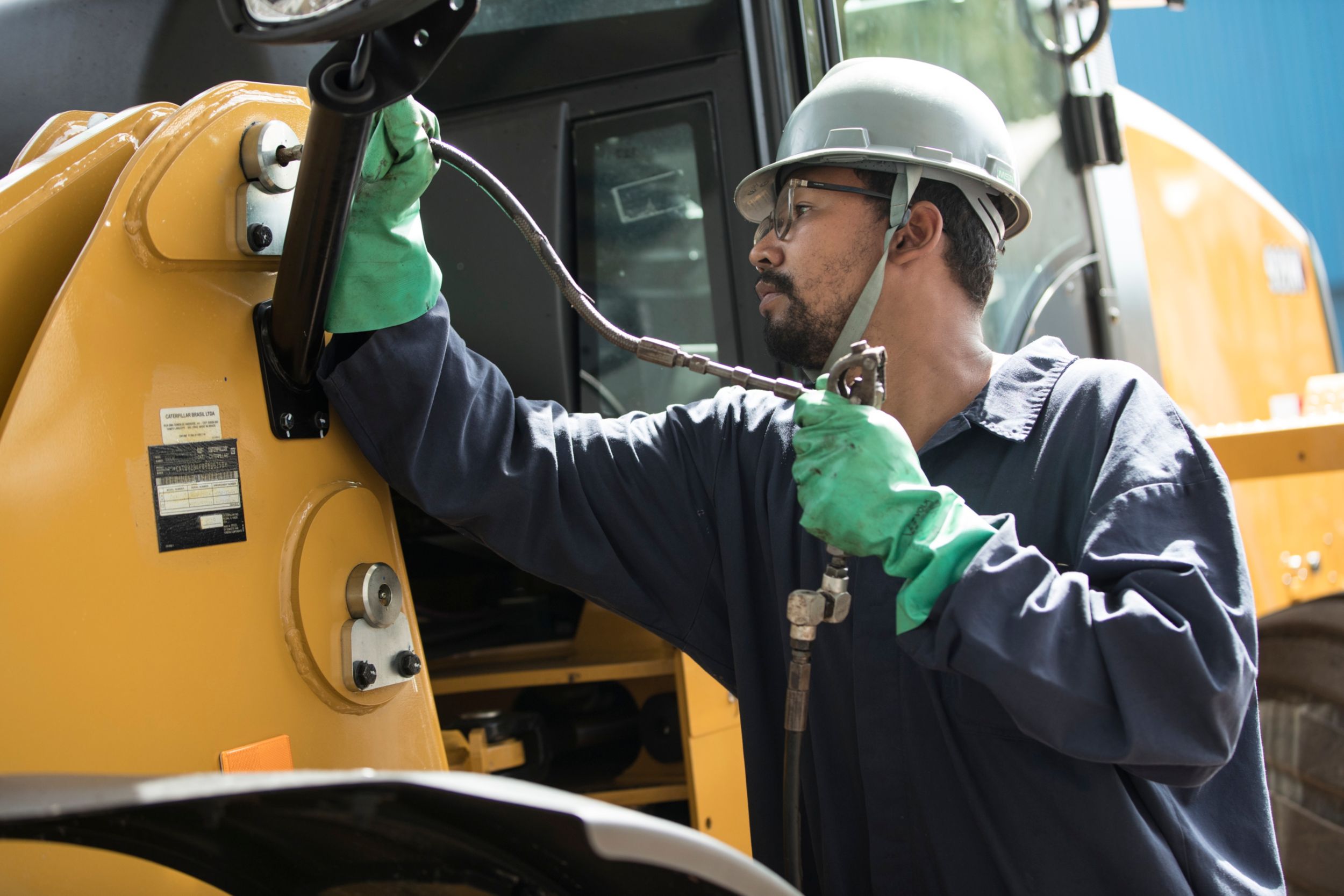person performing maintenance and service on a compact wheel loader