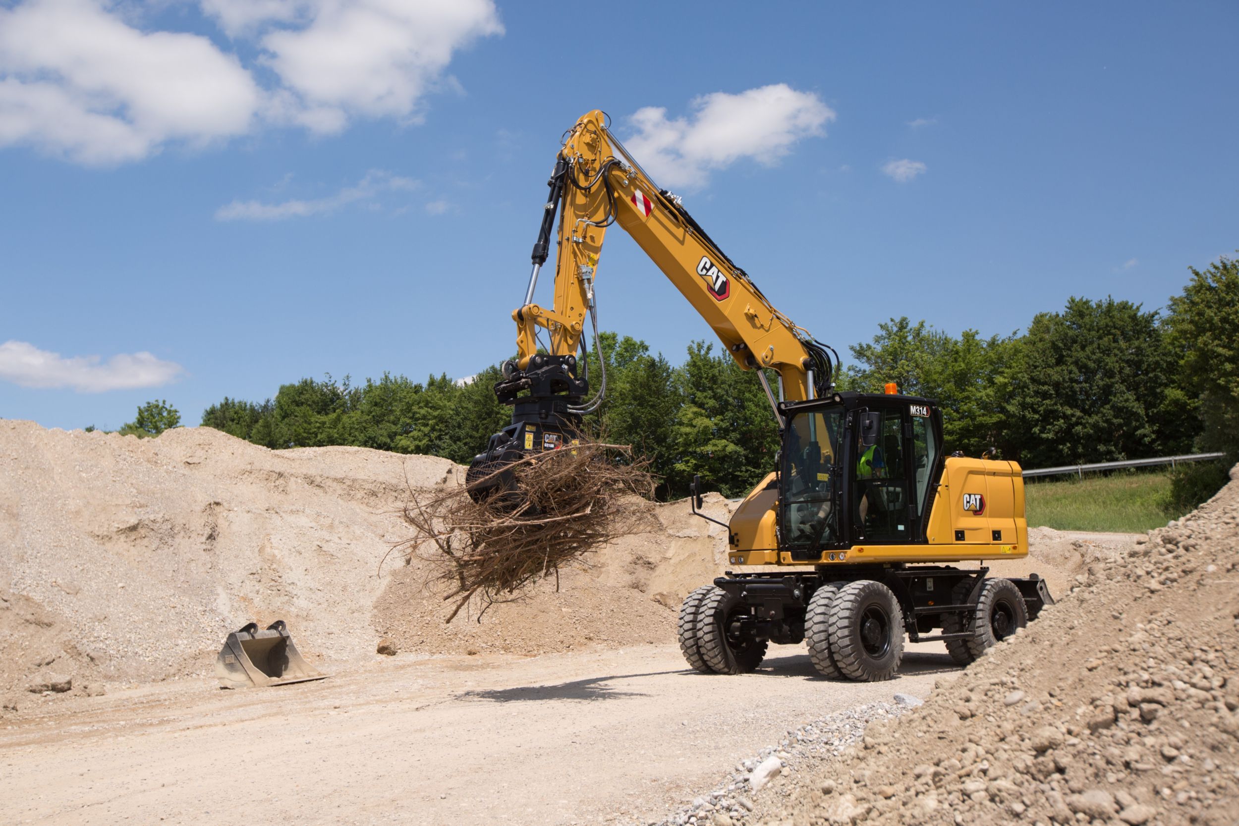 M314 Wheeled Excavator moving debris with grapple