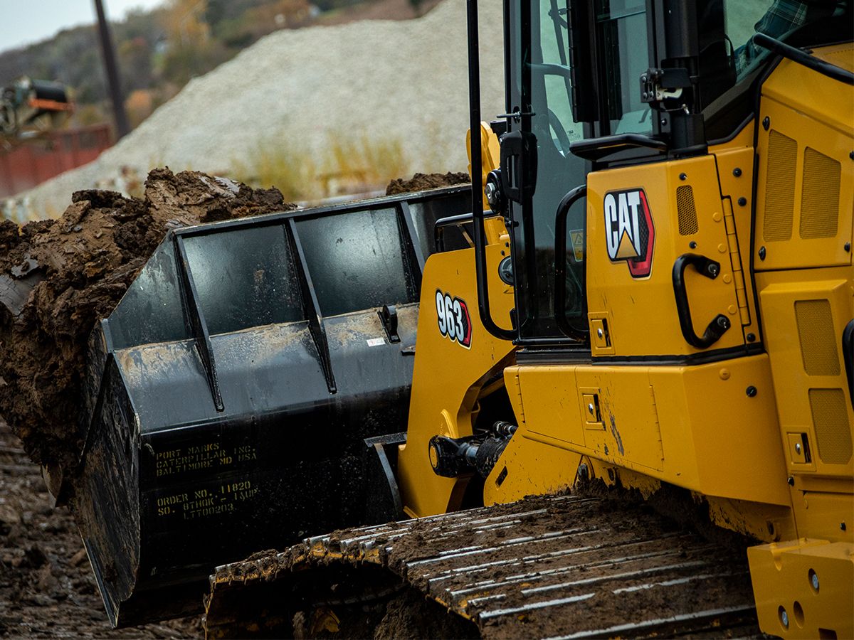 Cat crawler loader carries a heavy bucket of dirt