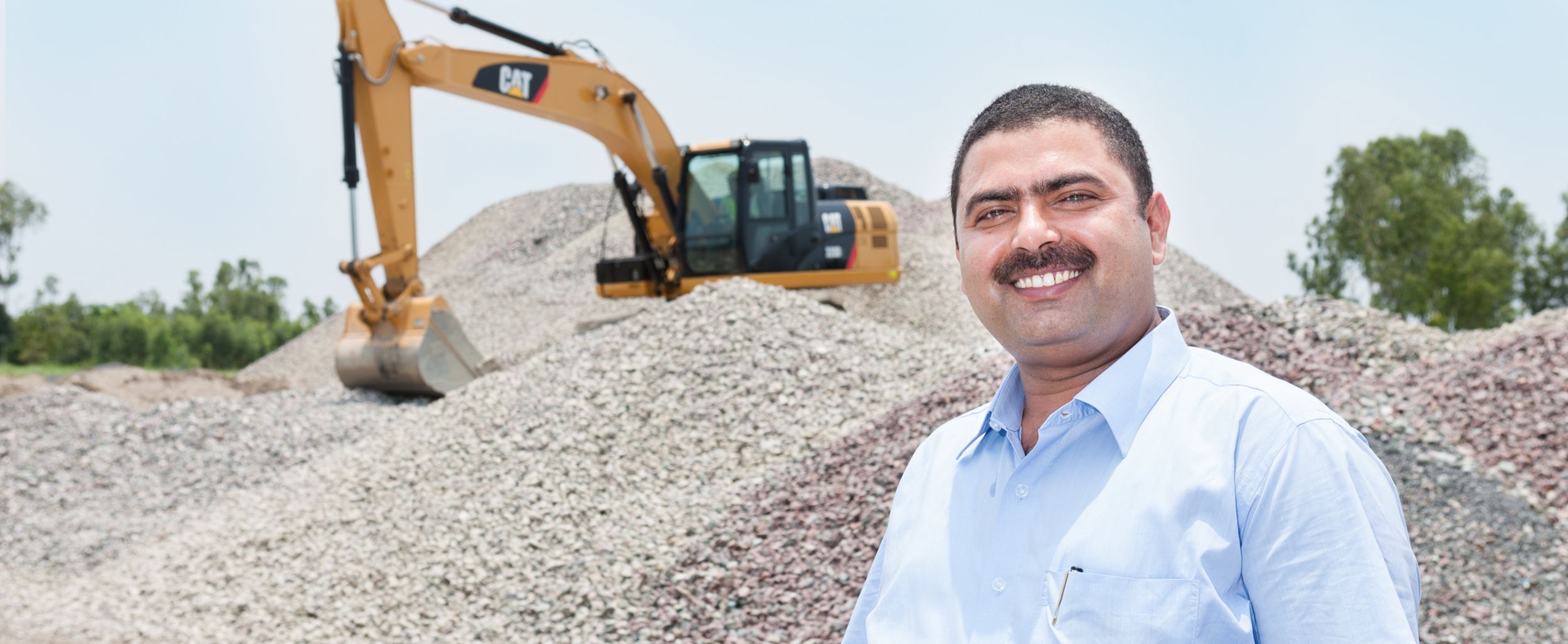 Male customer using Ipad with Excavator working in the background