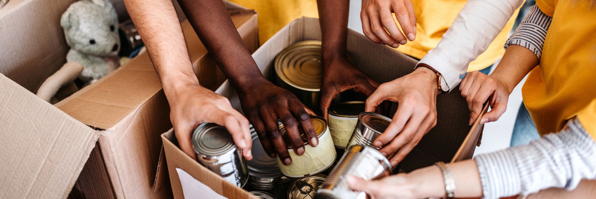 mãos colocando enlatados em uma caixa
