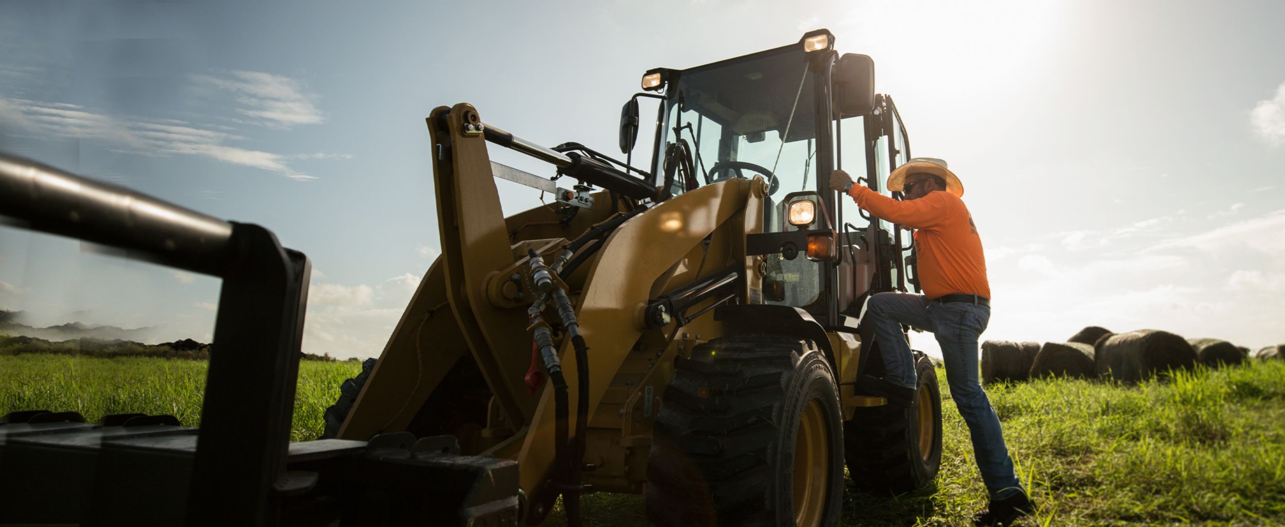 Younger male customer on a jobsite facing forward with a mini excavator working in the background