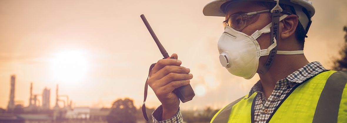 Worker with mask talking into walkie-talkie