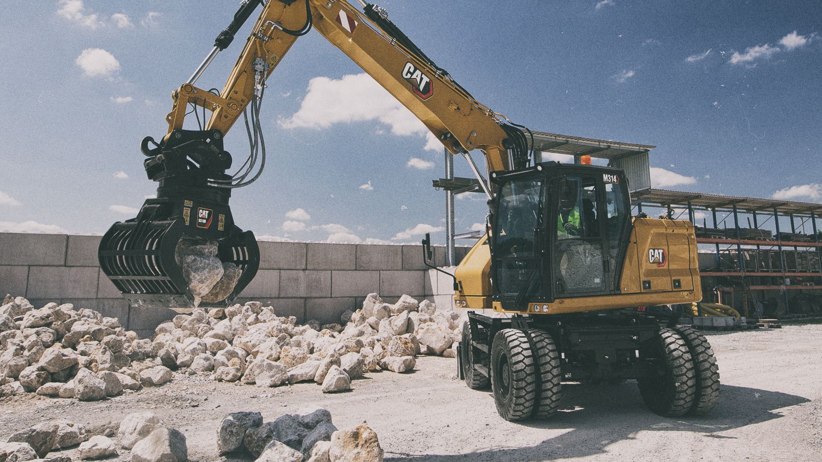 M314 Excavator picking up stones on jobsite
