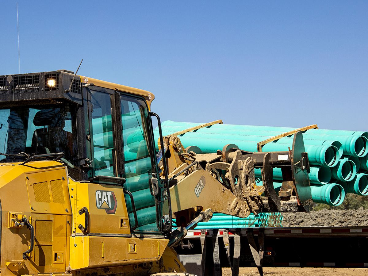 Cat 953 track loader fitted with forks to carry pipe