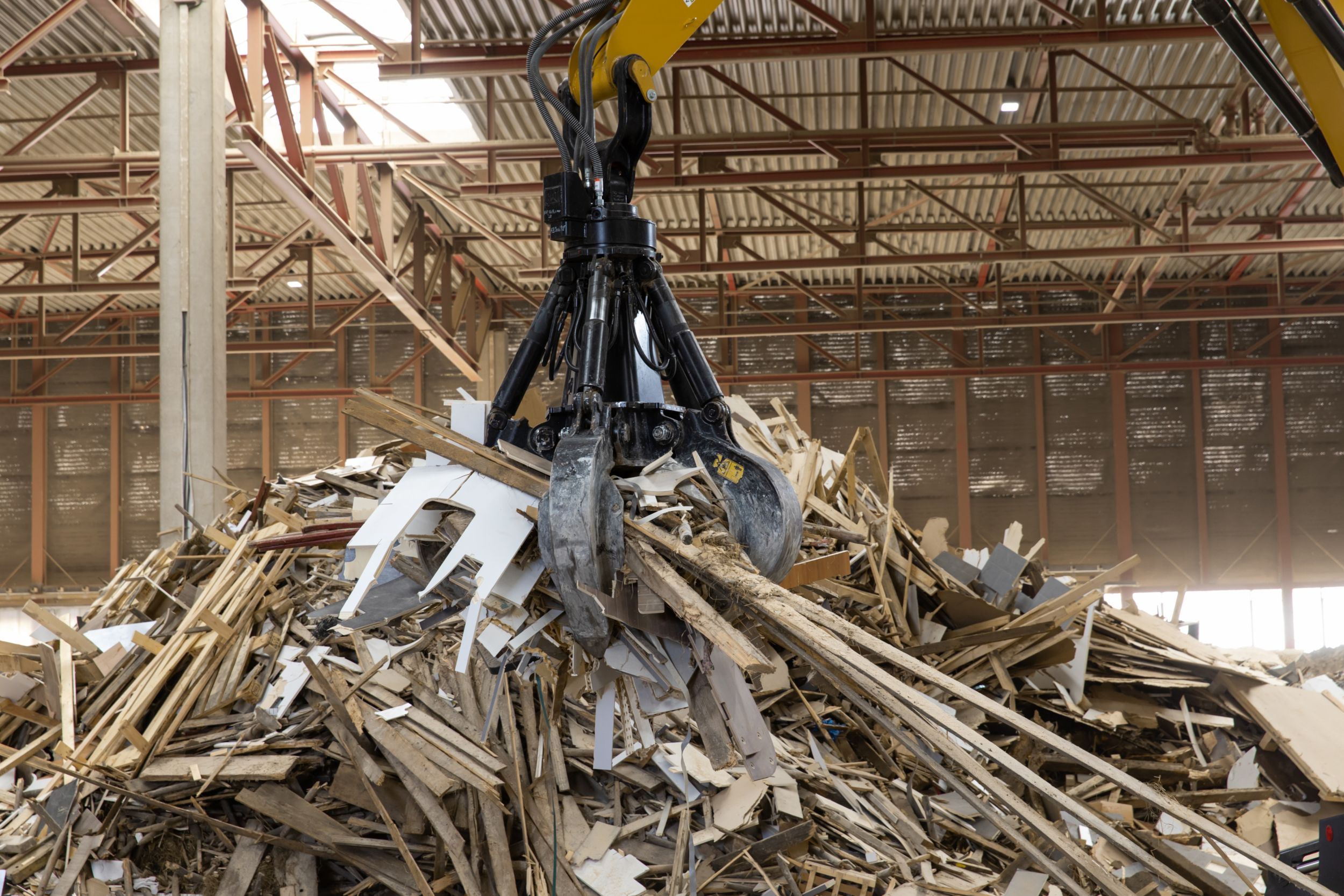 MH3024 lyfter upp bitar från en hög med trä