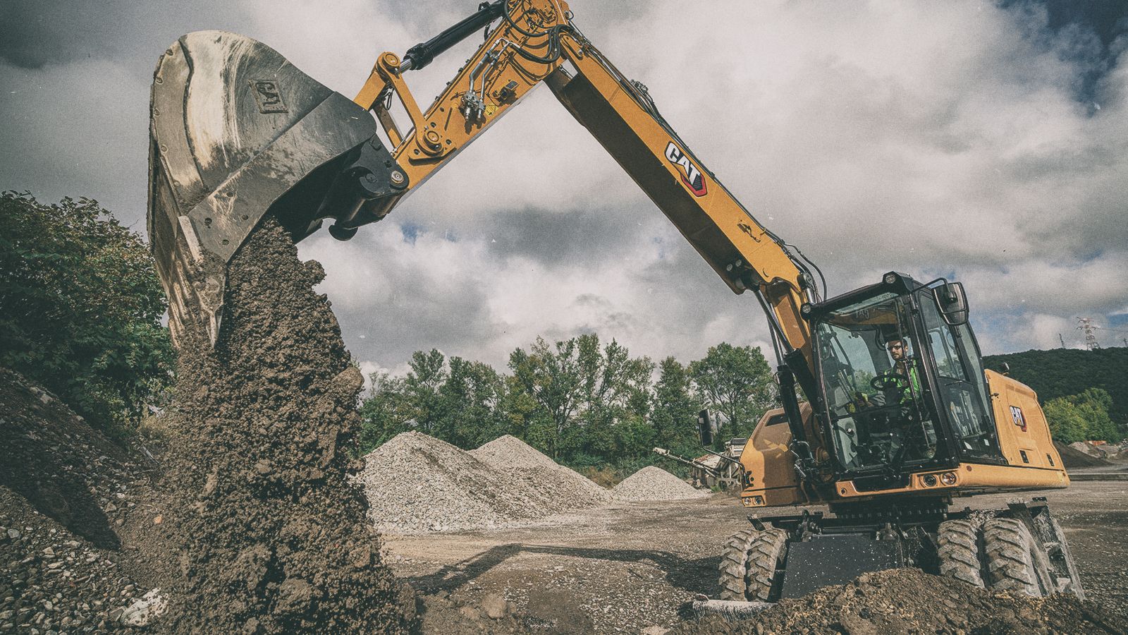 M316 Excavator pouring dirt on jobsite