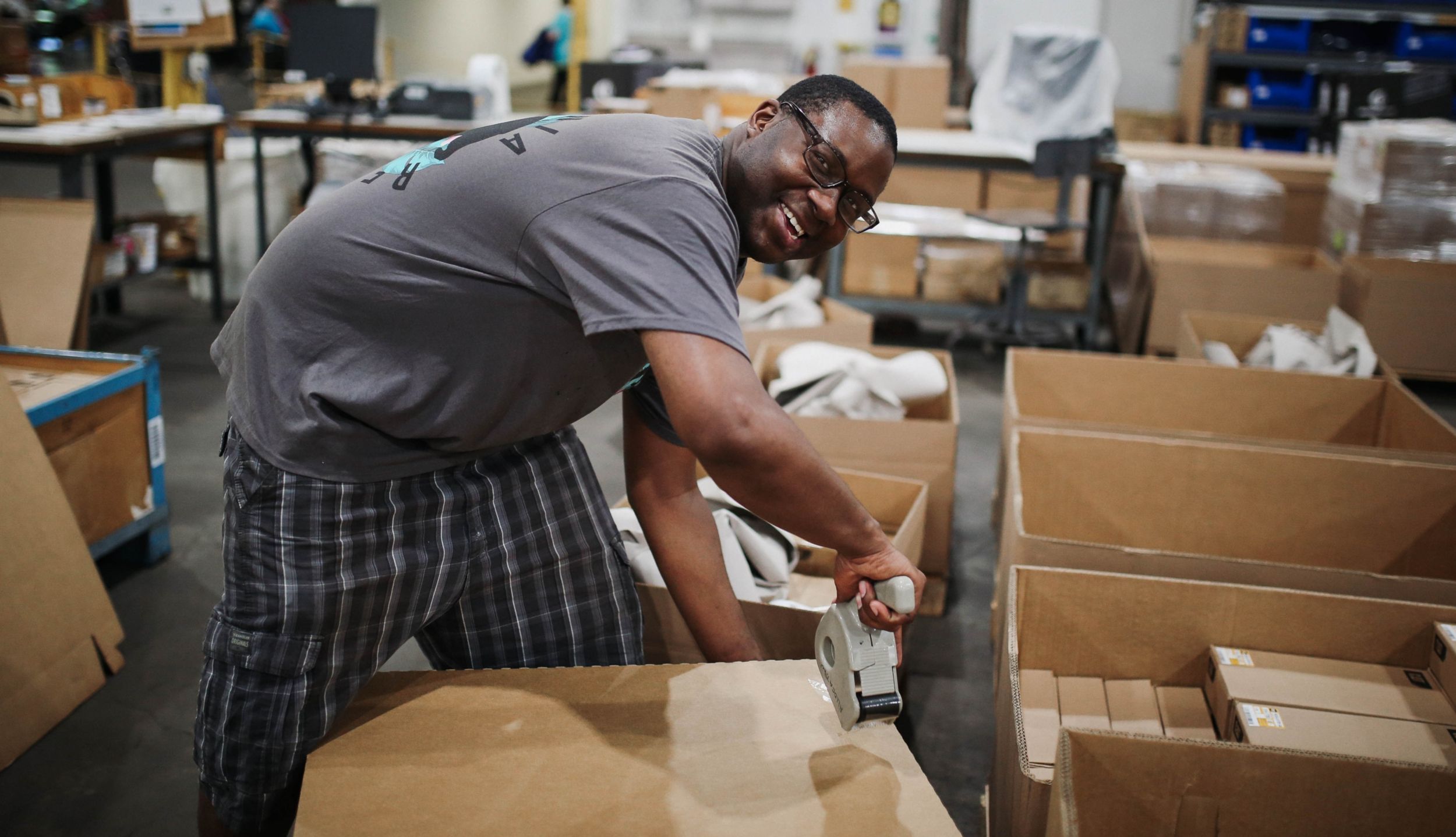 Man smiling while taping box