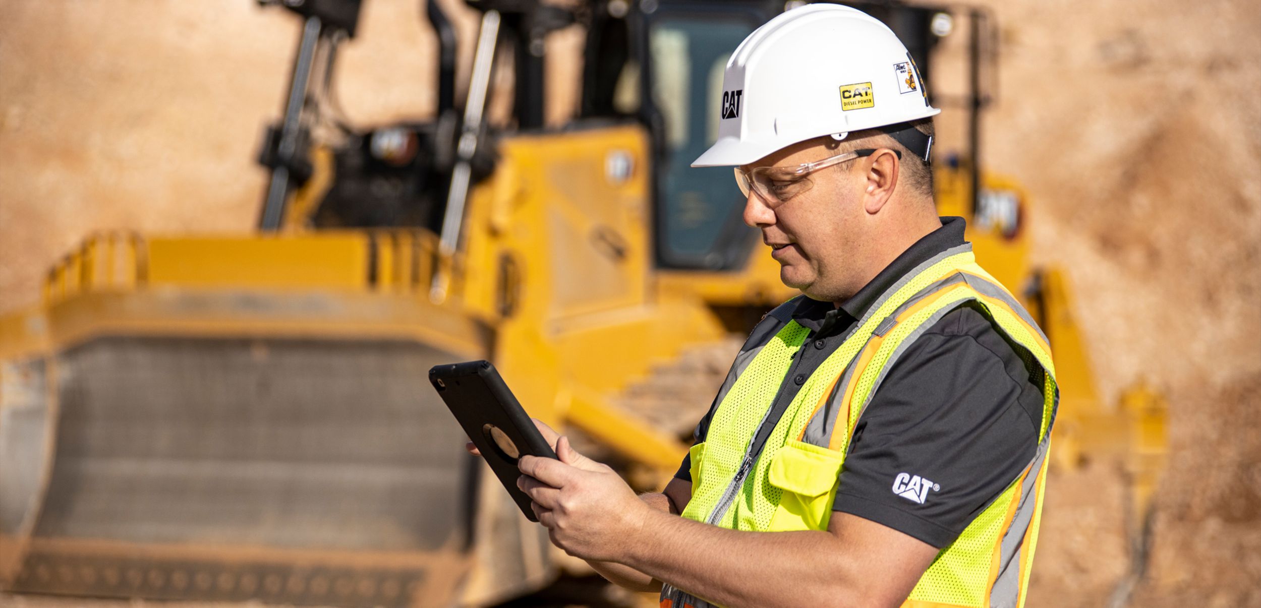 Cliente utilizando un iPad en el sitio de trabajo con la excavadora operando en segundo plano