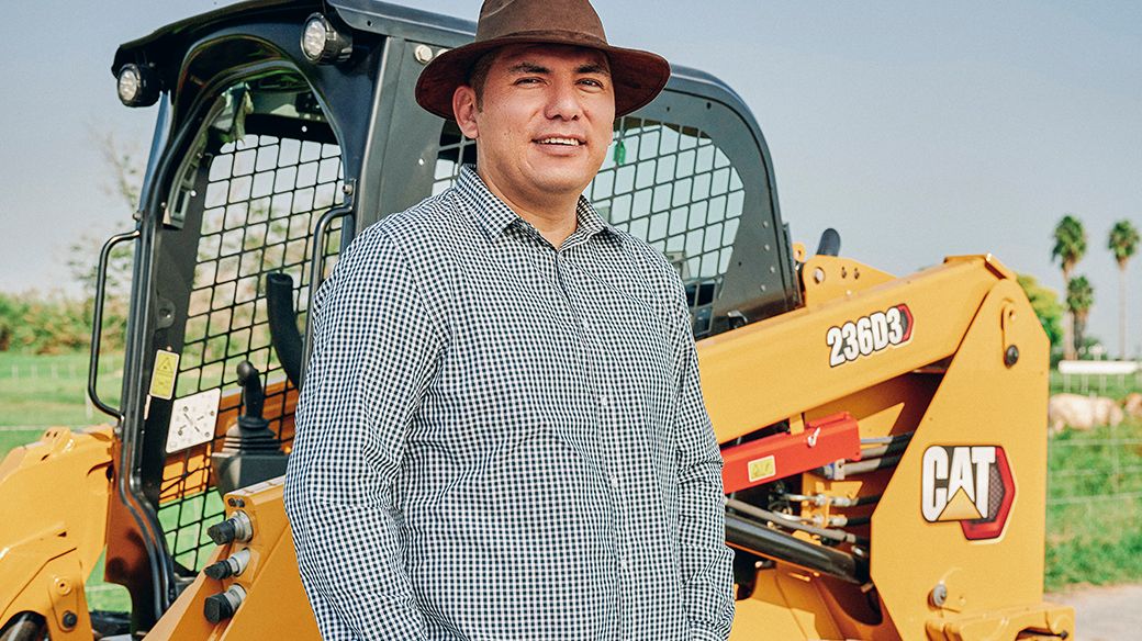 Male customer using Ipad with Excavator working in the background