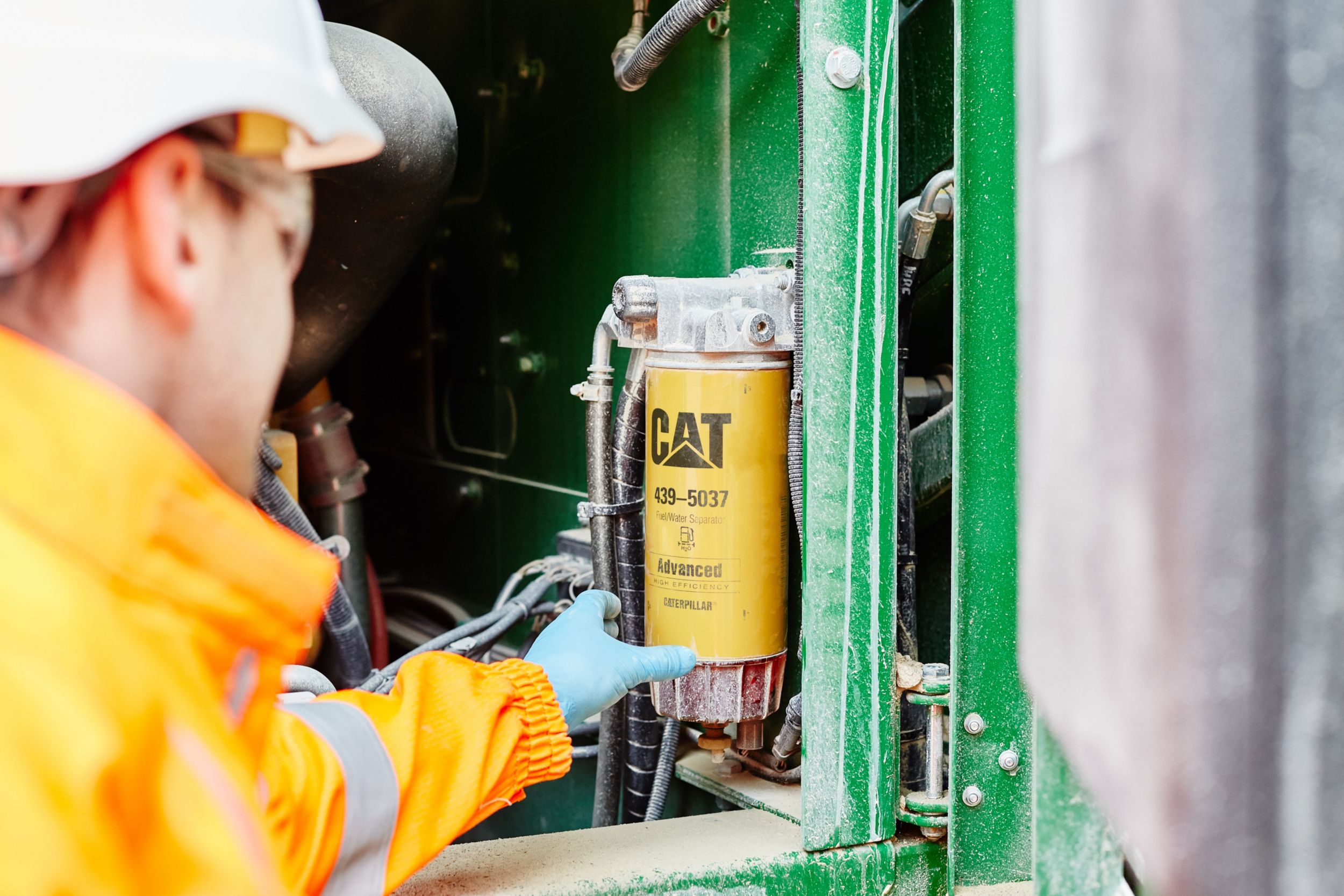 Man working on engine with Cat components, Fuel/Water Separator, 439-5037