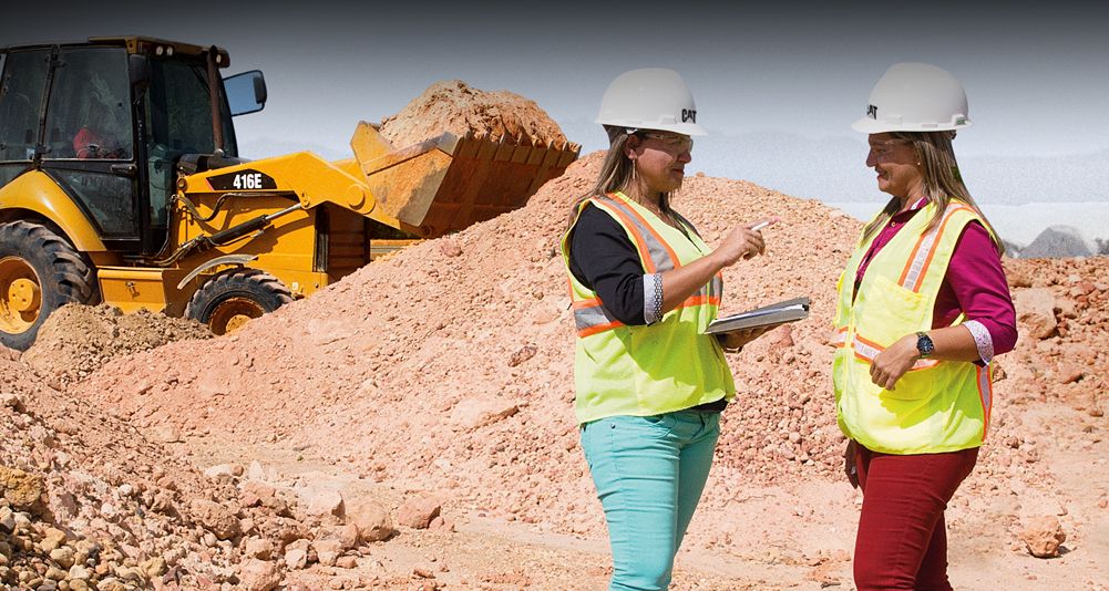 Клиент использует Ipad на стройке с экскаватором, работающим на заднем плане