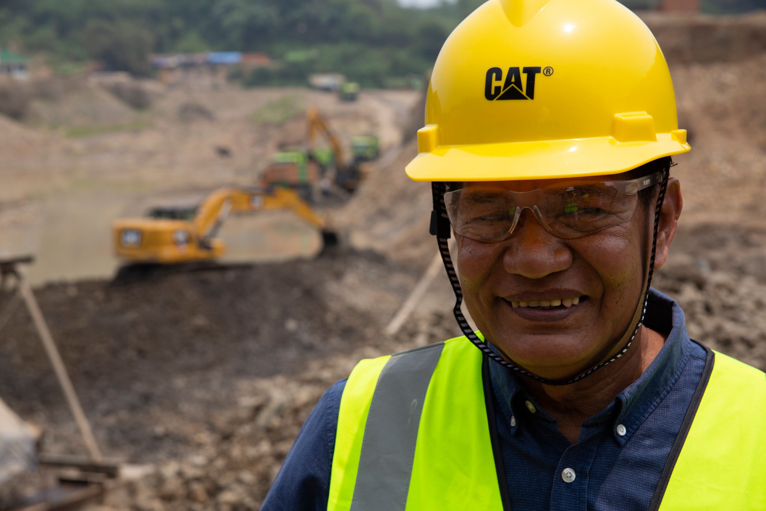 Male customer using Ipad with Excavator working in the background