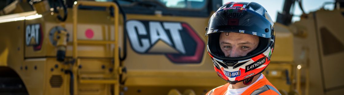 MotoGP rider Jack Miller giving thumbs up while standing in front of Cat® machines