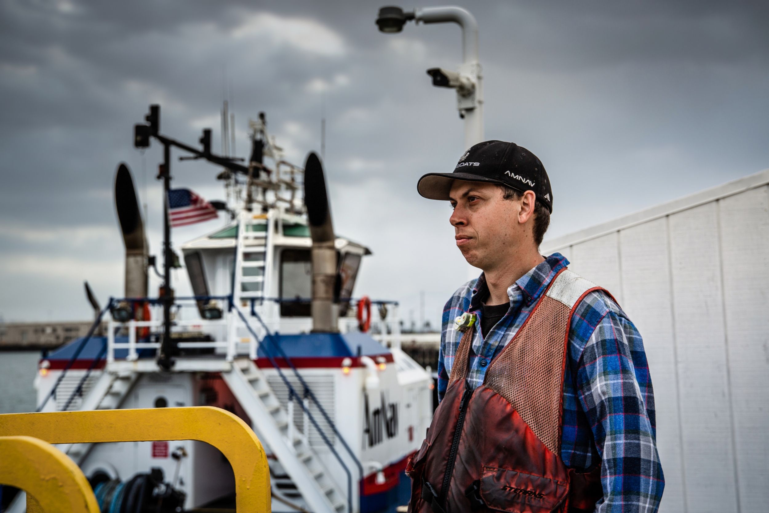 Fisherman standing next to boat and looking at the water
