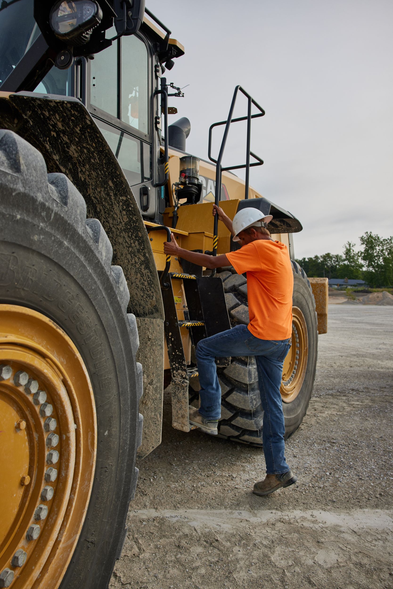 Un conducteur montant dans une chargeuse sur pneu Caterpillar. Il est un acteur important pour vous permettre d'économiser sur votre consommation de carburant sur vos chantiers