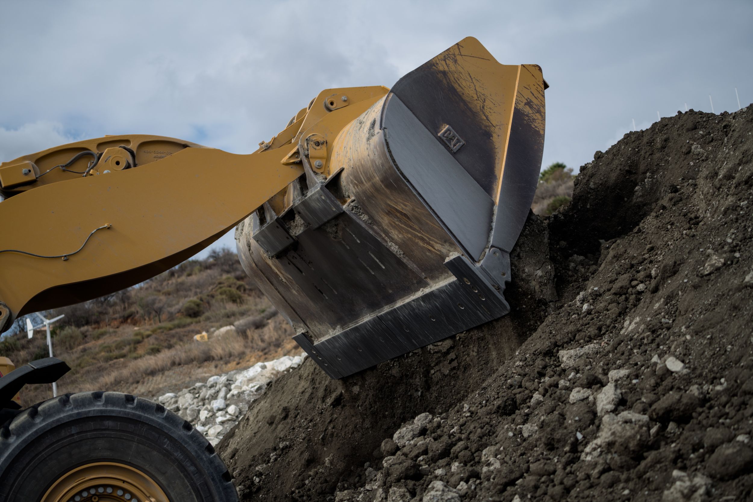 Wheel loader dropping dirt onto larger pile of dirt