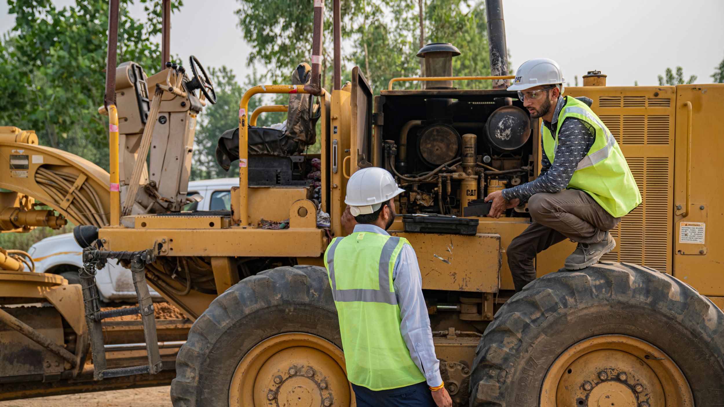 Two Cat® technicians doing repairs on the engine of a stationary machine