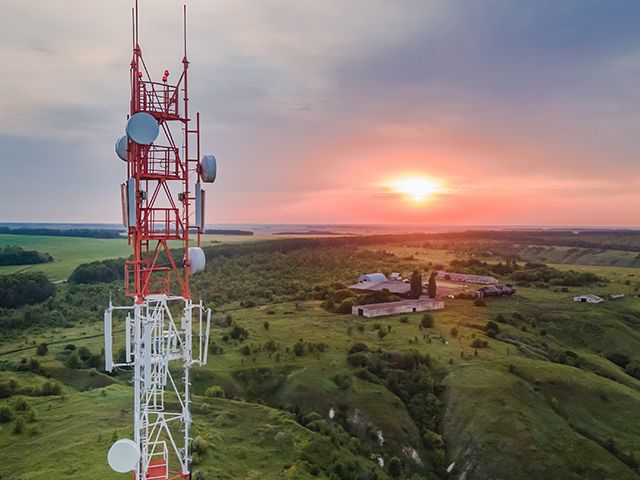 A telecommunications tower with a rural backdrop