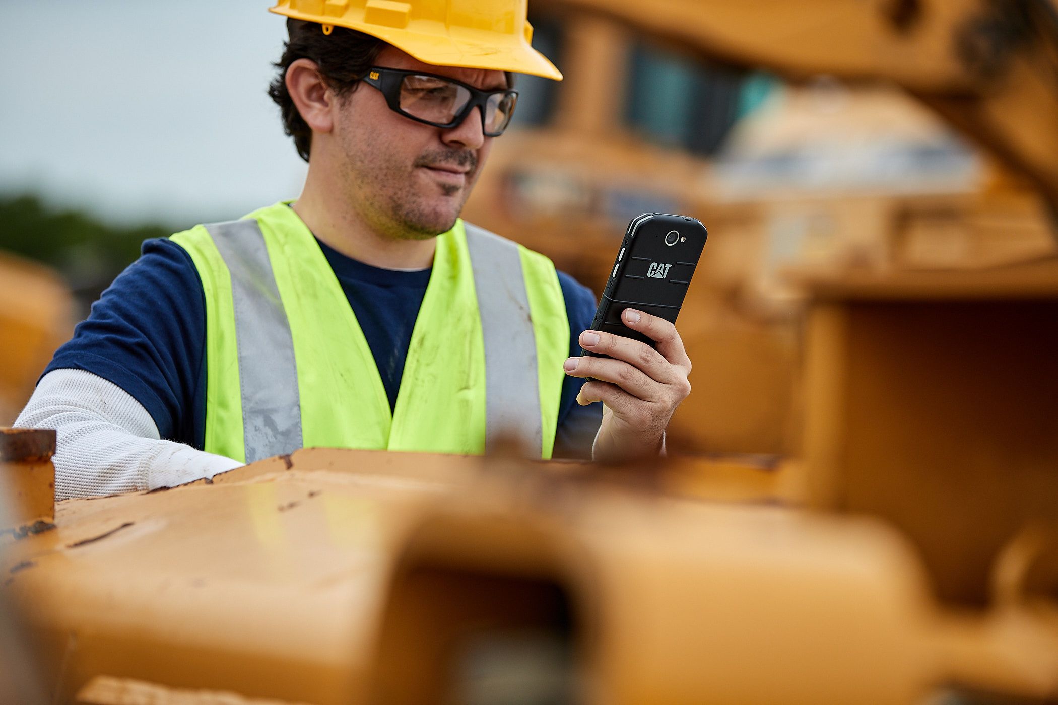 Customer using ipad on jobsite with excavator working in the background