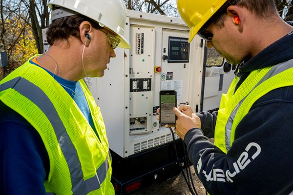 two men working on a genset control panel