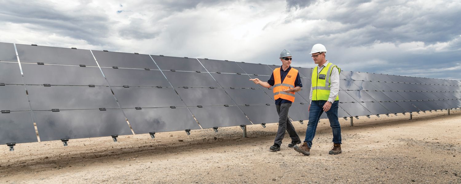 Men walking in front of solar panel field