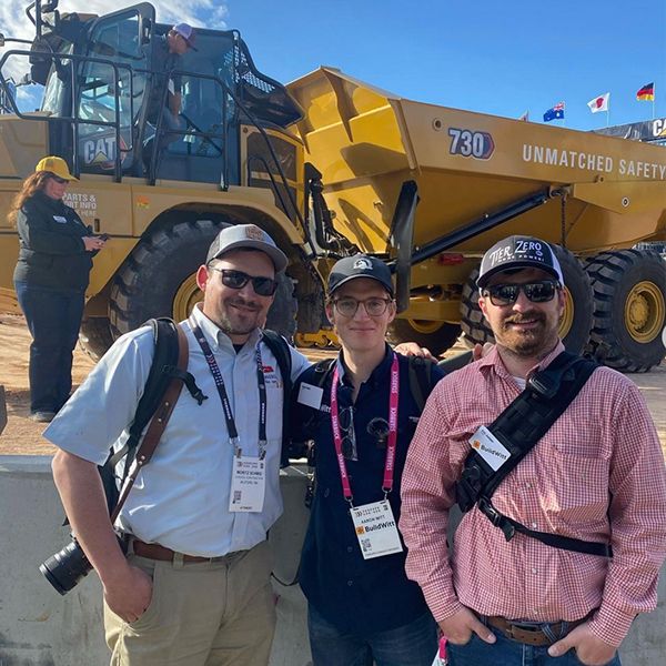 Three ConExpo show attendees pose outside of Operator Stadium