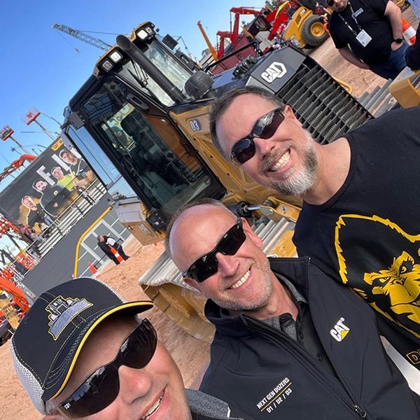 Two Caterpillar show workers pose with ConExpo show attendee Stanley